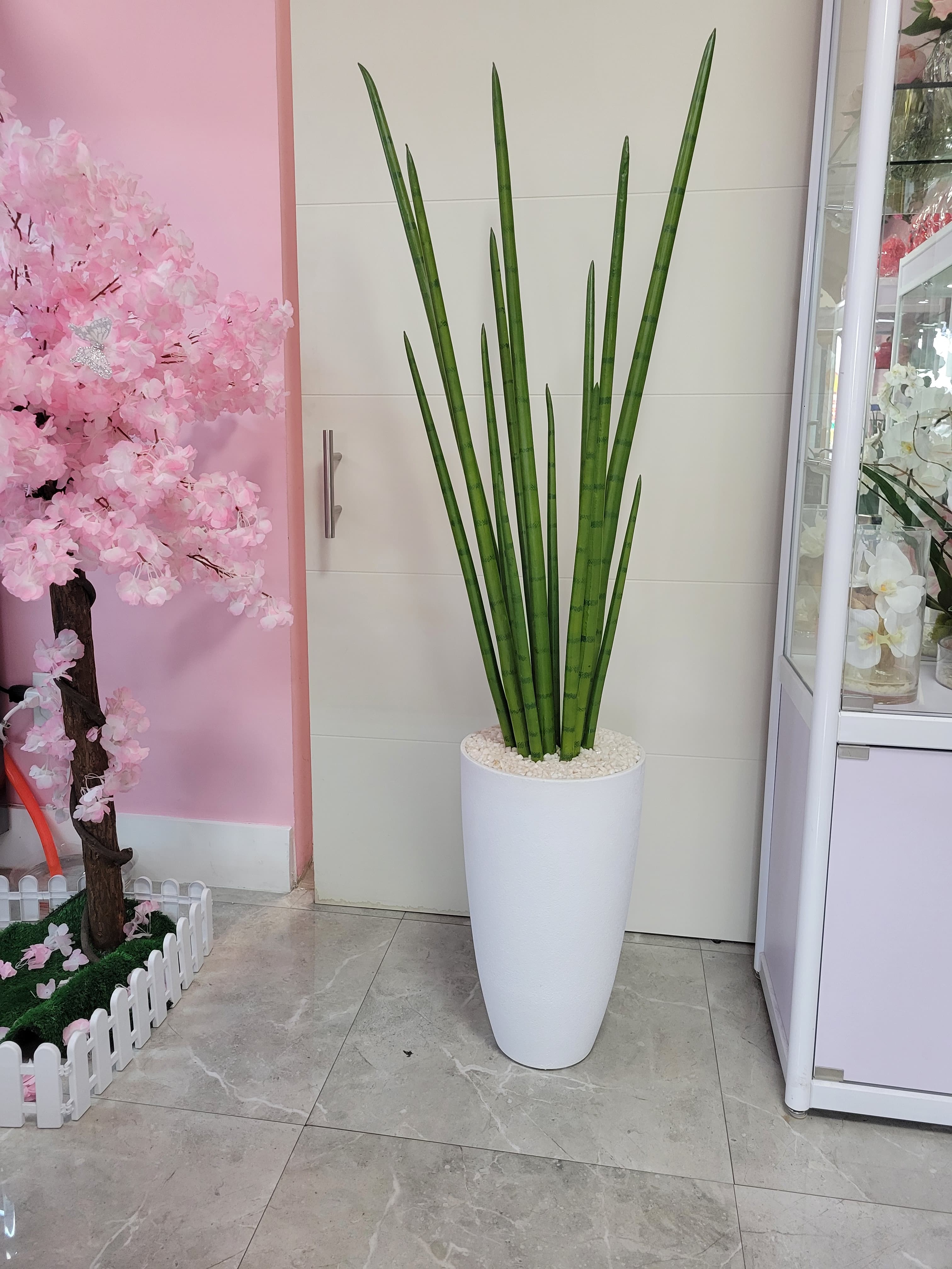 Artificial snake plant on white fiberstone base.